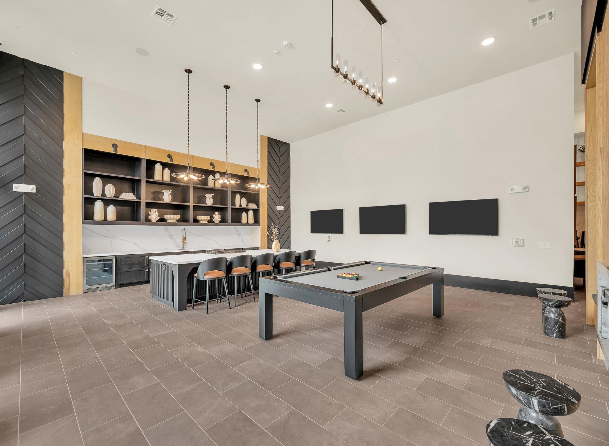 Camber Ridge Modern game room with a pool table, bar area with stools, shelves, and pendant lighting. Neutral color scheme.