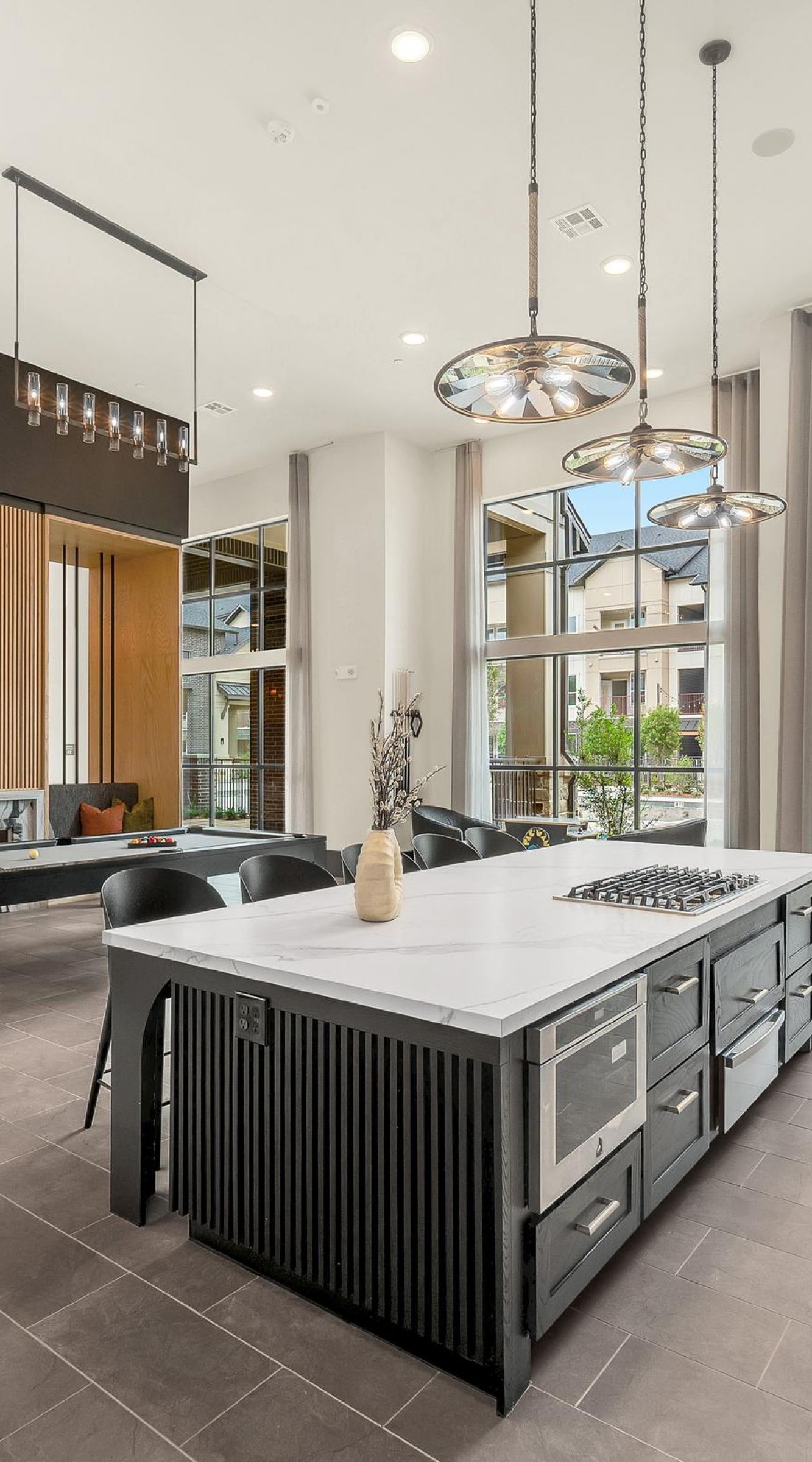 Camber Ridge Modern communal lounge with high ceilings, pool table, seating area, and large windows overlooking greenery.